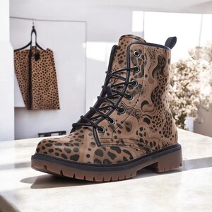 May include: A brown and black patterned combat boot with black laces. The boot has a round toe and a thick, brown sole. A matching tote bag hangs in the background. The boot's pattern resembles a leopard print.