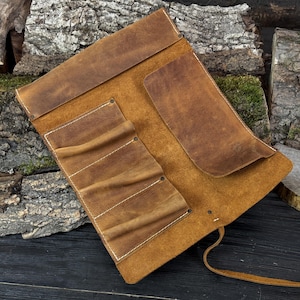 May include: A brown leather tool roll with multiple pockets and a flap closure. The roll features white stitching and a leather tie. The leather has a distressed appearance.