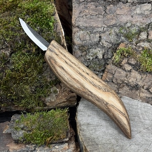 May include: A handcrafted knife with a curved, wooden handle and a silver blade. The handle is made of light brown wood with dark brown grain patterns. The knife is designed for carving or other detailed work.