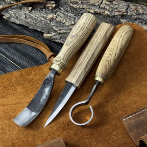 May include: A white ceramic mug with a black handle and the text "But First, Coffee" in a black, handwritten-style font. The mug is on a white surface.