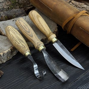 Puede incluir: Una taza de cerámica blanca con un asa negra y el texto "But First, Coffee" en negro, con una fuente de estilo manuscrito. La taza está sobre una superficie blanca.