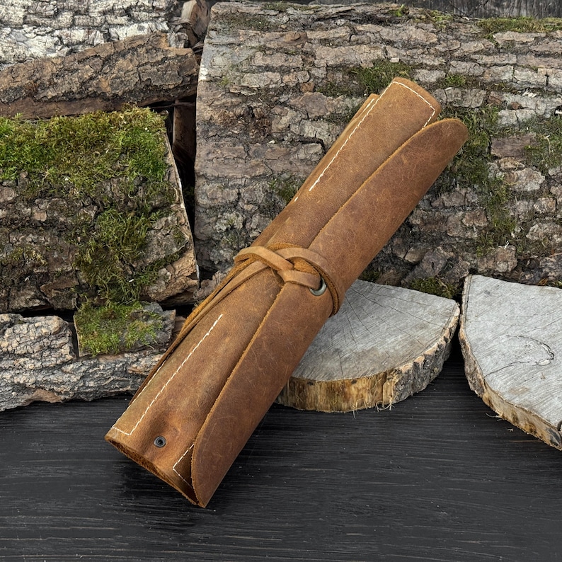 Rolled leather tool case with hand-forged spoon carving tools for kuksa and bowl carving.