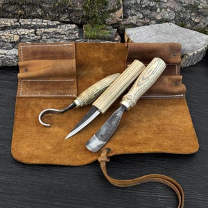 Hand-forged wood carving tools on leather mat, hook knife and gouge for spoon carving work.