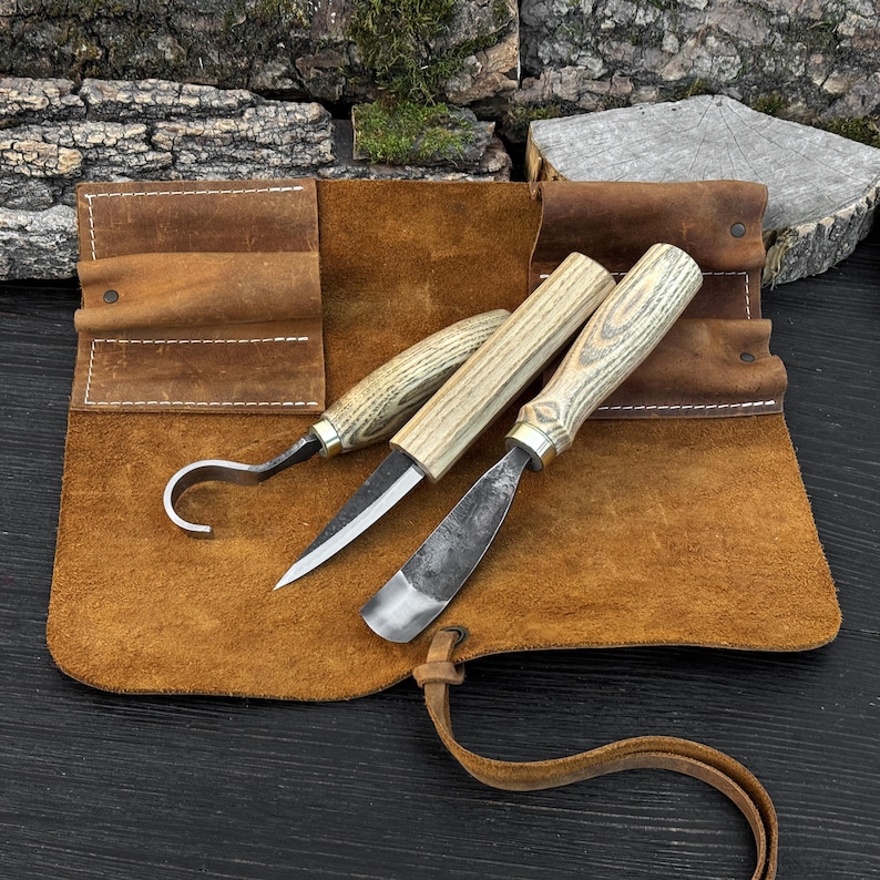 Hand-forged wood carving tools on leather mat, hook knife and gouge for spoon carving work.