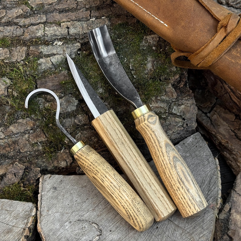 Spoon carving kit with scorp-style hook knife and gouge, wood carving tools on bark.