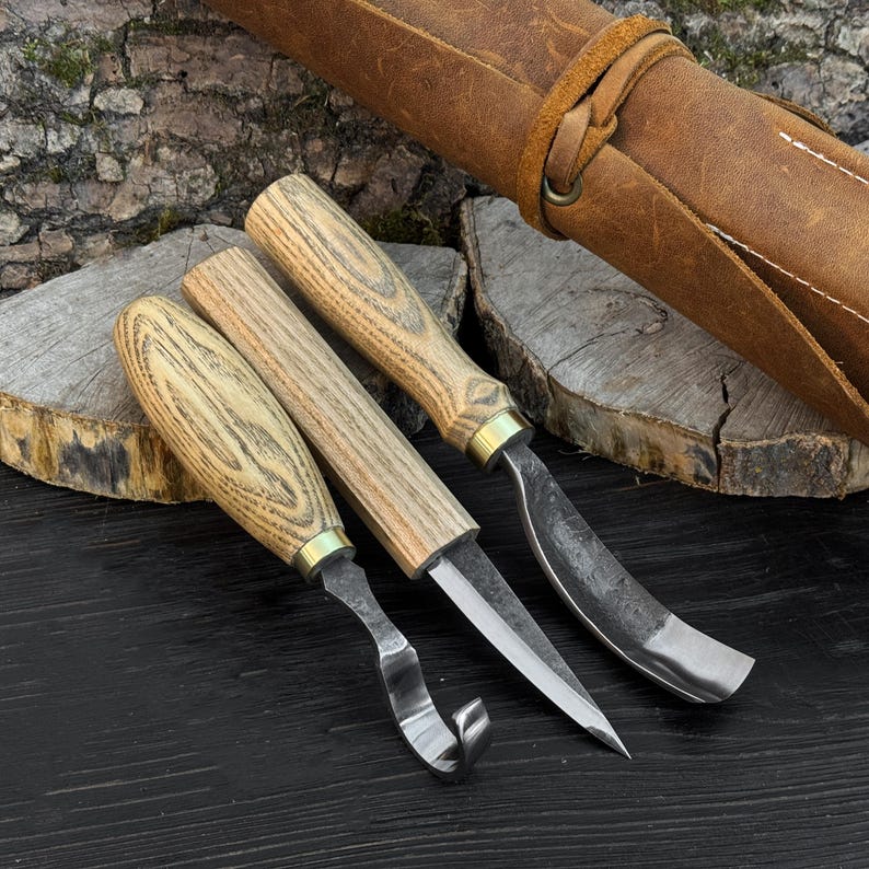 Close-up of forged spoon carving tools, curved blades and sloyd knife for wood carving.