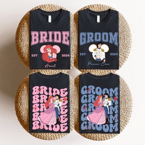 May include: Four black t-shirts with wedding-themed designs. Two shirts say "BRIDE" and "GROOM" with cartoon images of Ariel and Prince Eric. The other two shirts have the words "BRIDE" and "GROOM" repeated in a retro font, with images of the couple.