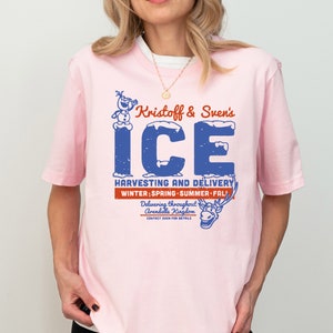 K&ouml;nnte beinhalten: Pinkes T-Shirt mit einer blauen und wei&szlig;en Grafik von Kristoff und Svens Eisernte und -lieferung. Die Grafik zeigt einen Schneemann und ein Rentier. Der Text lautet "Kristoff & Sven's ICE HARVESTING AND DELIVERY WINTER; SPRING SUMMER FALL Delivering throughout Arendelle Kingdom"