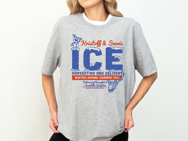 K&ouml;nnte beinhalten: Graues T-Shirt mit einer blauen und roten Grafik von Olaf und Sven, die Eis liefern. Der Text lautet "Kristoff & Sven's ICE HARVESTING AND DELIVERY WINTER; SPRING SUMMER FALL! Delivering throughout Arendelle Kingdom."