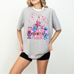 a woman wearing a gray shirt with a pink castle on it