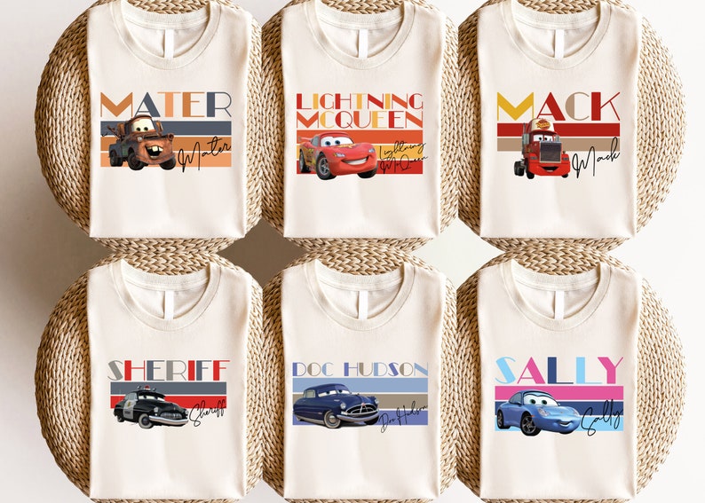 K&ouml;nnte beinhalten: Sechs wei&szlig;e T-Shirts mit verschiedenen Cars-Charakteren bedruckt. Die Charaktere sind Mater, Lightning McQueen, Mack, Sheriff, Doc Hudson und Sally. Jedes Shirt hat ein Retro-Design mit einem bunten Streifenmuster und dem Namen des Charakters in fetten Buchstaben.