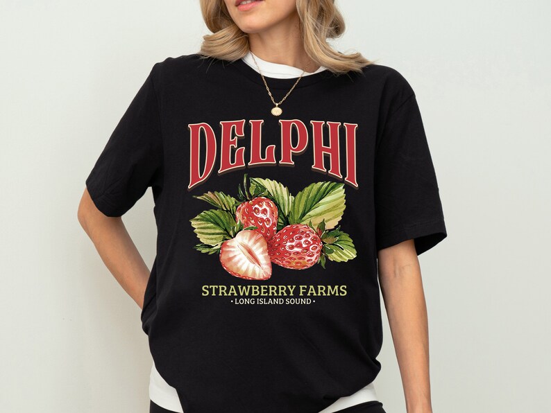Puede incluir: Camiseta negra con un gr&aacute;fico rojo de fresas y el texto "DELPHI STRAWBERRY FARMS - LONG ISLAND SOUND -"