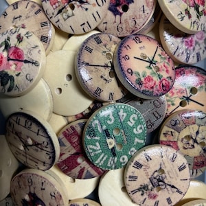 Könnte beinhalten: Eine Sammlung von Holzknöpfen mit Zifferblatt- und Blumendesigns. Die Knöpfe zeigen römische Ziffern, Uhrzeiger und verschiedene dekorative Elemente, darunter Rosen und einen Hahn. Einige Knöpfe haben einen grünen Hintergrund mit weißen Zahlen.