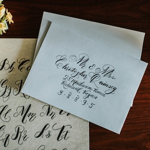 May include: A blue envelope with a handwritten address in black ink. The address reads "Mr. & Mrs. Christopher Quinsey, 25 Meadowview Terrace, Richmond, Virginia, 3.8.8.9.5".