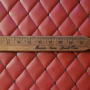 Puede incluir: Una paleta de madera con una regla grabada a lo largo del borde superior, que mide hasta 30,5 cm. La paleta tiene las frases "madly & deeply" y "Measure Twice, Spank Once" grabadas en la madera. La paleta está sobre un fondo rojo con patrón de diamantes.