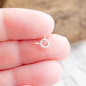 May include: Silver jump ring with a round opening. The ring is about 1/2 inch in diameter.