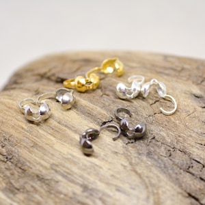 May include: Four sets of silver and gold metal bead caps. Each set has two pieces that connect to form a bead cap.