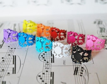 May include: Ten colorful rings with a filigree design. The rings are made of metal and have a smooth, painted finish. The colors of the rings are purple, blue, turquoise, white, black, pink, hot pink, orange, yellow, and red.