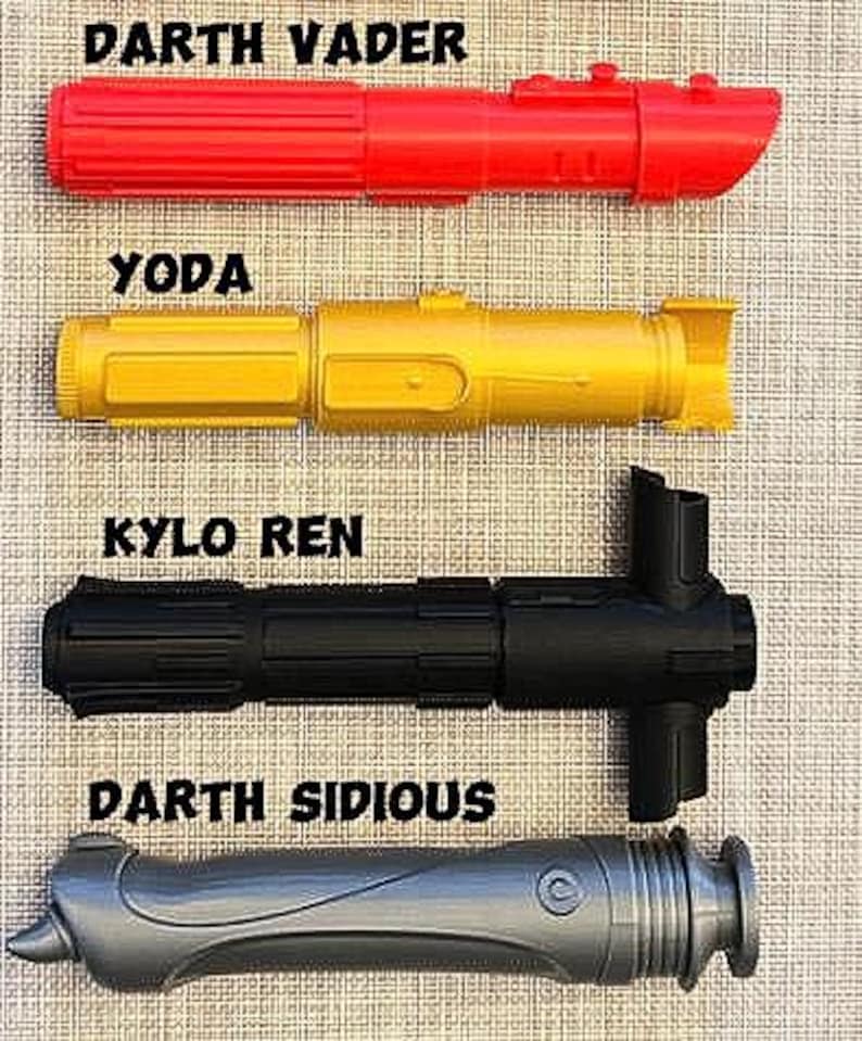 K&ouml;nnte beinhalten: Vier Spielzeug-Lichtschwerter, eines rot, eines gelb, eines schwarz und eines grau, mit den Namen Darth Vader, Yoda, Kylo Ren und Darth Sidious, die &uuml;ber jedem gedruckt sind.