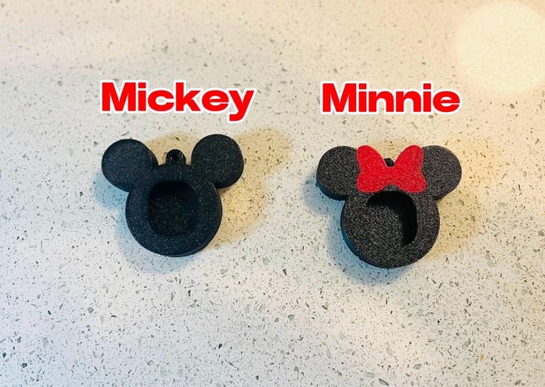 May include: Two black foam cutouts of Mickey Mouse and Minnie Mouse. Mickey Mouse has large round ears and Minnie Mouse has a red bow on her head.
