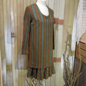May include: A vintage-style dress with long sleeves and a scoop neckline. The dress features vertical stripes in shades of teal, orange, and olive green. The skirt has a ruffled hem. The dress is displayed on a mannequin.