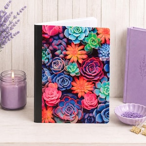 May include: A notebook featuring a vibrant, multi-colored succulent pattern on the cover. The design displays a dense arrangement of various succulent plants in shades of pink, orange, blue, and green. The notebook has a solid black spine.