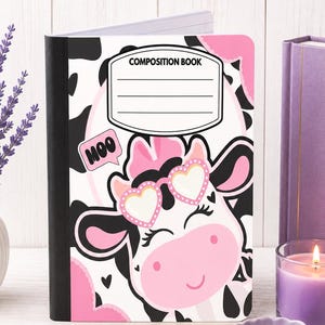 May include: A composition book featuring a black and white cow print pattern with pink accents. The cover displays a cartoon cow wearing heart-shaped glasses and a speech bubble with the text MOO. A white label area at the top reads COMPOSITION BOOK.
