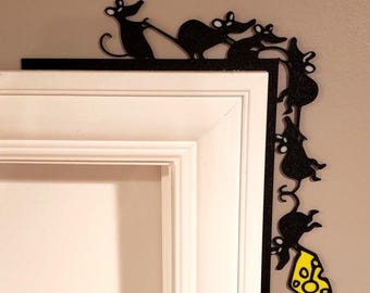 May include: A black glittery L-shaped door corner decoration featuring a line of five mice silhouettes. The mice are connected in a sequence, with the bottom mouse holding a bright yellow piece of Swiss cheese with visible holes in the design.