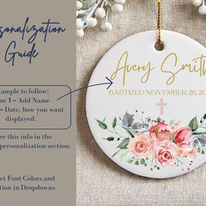 May include: A white ceramic ornament with a floral design and gold lettering. The ornament says "Avery Smith Baptized November 26, 2024".