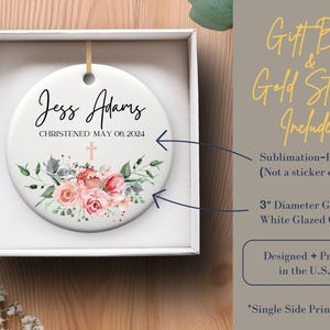 May include: White ceramic ornament with a floral design and the text "Jess Adams Christened May 06, 2024". The ornament is 3 inches in diameter and comes in a gift box with a gold string.