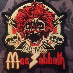 May include: Black and red embroidered patch with a skull with red hair, two smaller skulls, and the text "Black Sabbath" in yellow and red.