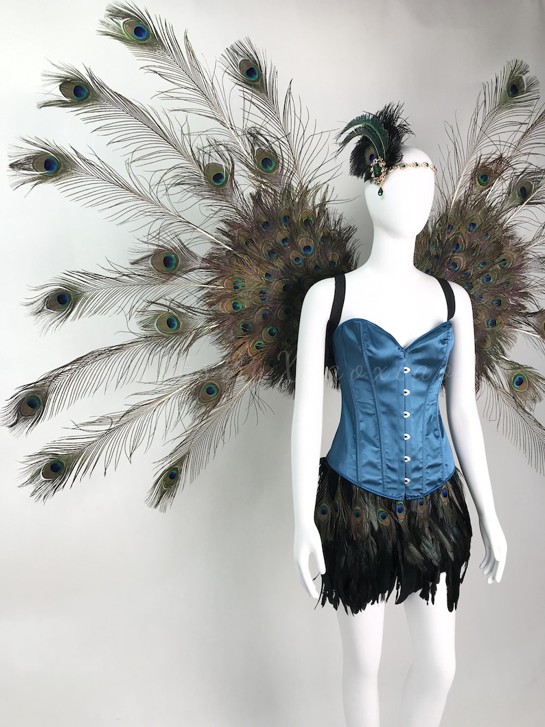 May include: A blue satin corset with a front busk closure, paired with a black feather skirt and large, expansive peacock feather wings. A matching headpiece features a small peacock feather plume and a decorative jewel accent.