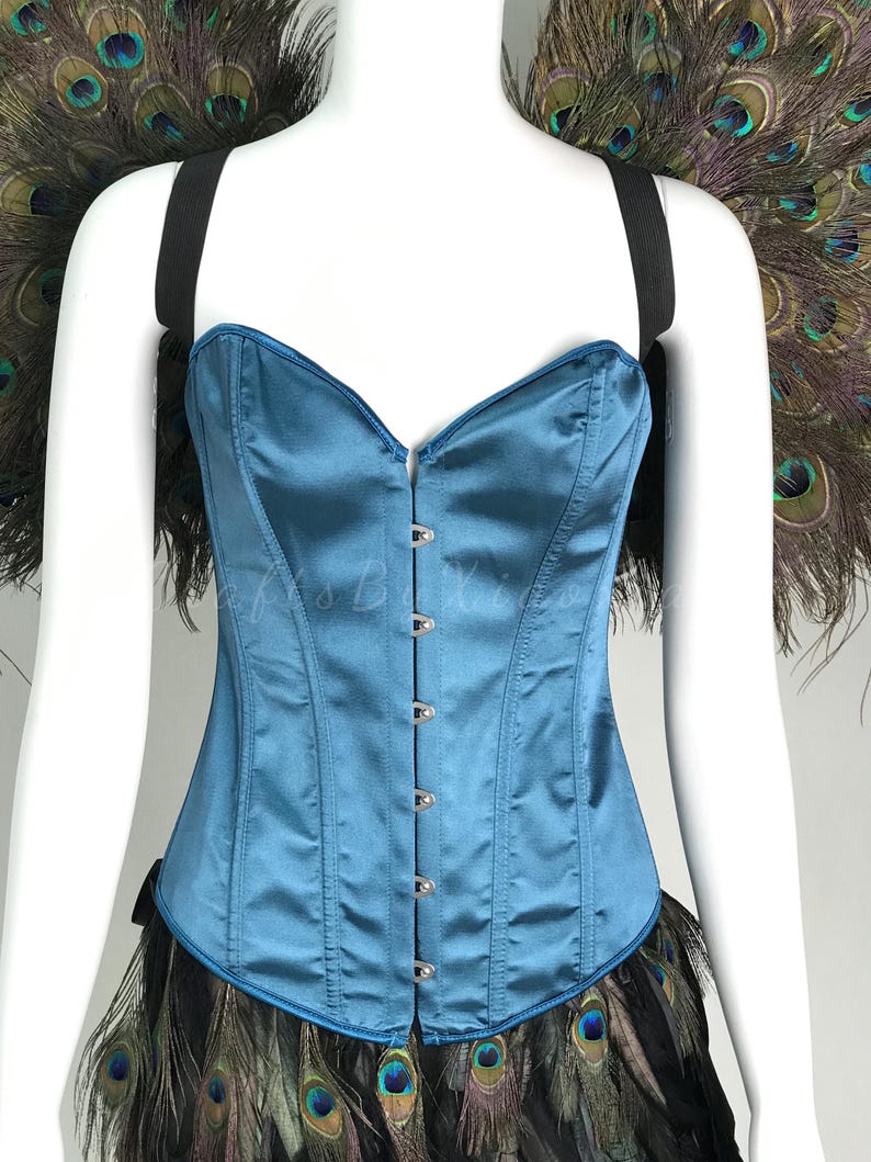 May include: A teal satin corset featuring a sweetheart neckline and a front metal hook-and-eye closure. The garment is accented with black elastic shoulder straps and a decorative trim of iridescent peacock feathers at the top and bottom edges.