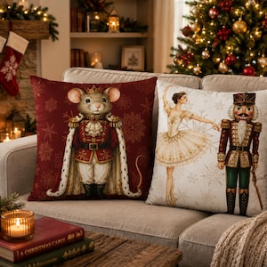 May include: Two square throw pillows featuring holiday themes. The left pillow is deep red with a mouse dressed as a royal nutcracker. The right pillow is cream-colored, displaying a ballerina and a nutcracker soldier, both accented with snowflakes.