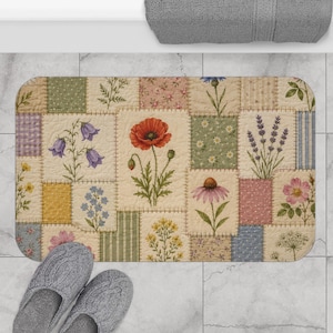May include: A rectangular bath mat featuring a patchwork design of various floral illustrations, including poppies, lavender, and daisies, set against a cream-colored background with quilted stitching and a pair of gray cable-knit slippers.