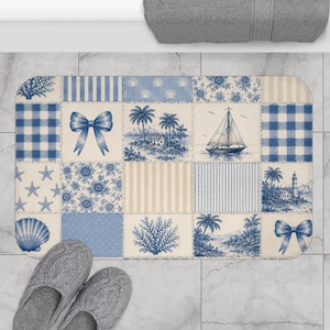 May include: A rectangular bath mat with a patchwork design featuring blue and white coastal-themed patterns. The mat includes images of seashells, bows, sailboats, and palm trees. The mat is approximately 30 inches long and 20 inches wide.