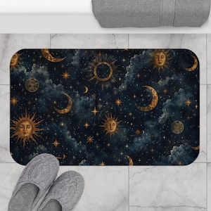Può includere: Un tappetino da bagno rettangolare con un design celeste con soli, lune e stelle su sfondo blu scuro. Il tappetino ha un bordo arrotondato ed è posizionato su un pavimento piastrellato. Sotto sono visibili delle pantofole grigie.