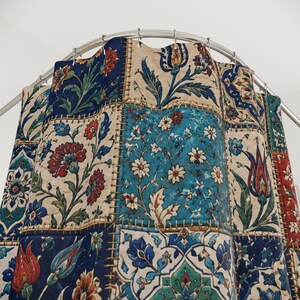 May include: A patchwork shower curtain with a floral design. The curtain features squares of various colors, including blue, cream, and red, with detailed floral patterns. The curtain is hanging from a curved metal rod.