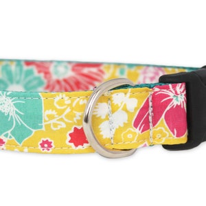 May include: A yellow, green, pink, and white floral dog collar with a black plastic buckle and silver metal D-ring.