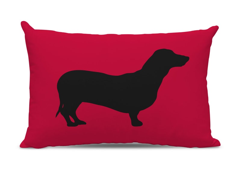 May include: Red throw pillow with a black silhouette of a dachshund.
