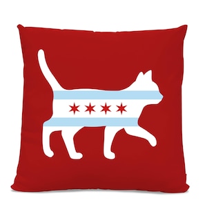 May include: Red throw pillow with a white silhouette of a cat wearing a Chicago flag design. The cat is facing right and has a long tail.