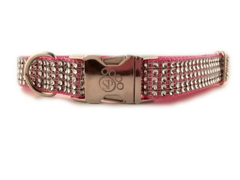 K&ouml;nnte beinhalten: Rosa Hundekette mit silbernen Strasssteinen und einer silbernen Schnalle mit dem Text "SP" und einem Pfotenabdruck.