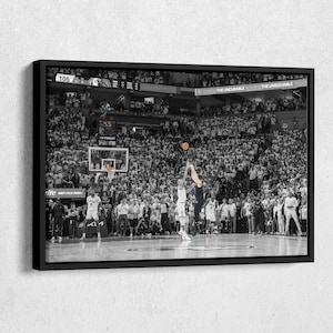 May include: A black and white photograph of a basketball game. A player in a white jersey is jumping to shoot the ball, while a player in a dark jersey is blocking the shot. The game is taking place in a large arena with a crowd of spectators. The scoreboard shows the score as 106. The text "DURING THE UNCURABLE SOIMING THE UNSOLVABLE TREAT" is displayed on the scoreboard.