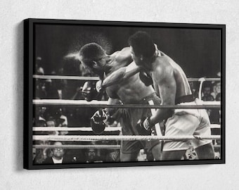 May include: Black and white photograph of two boxers in a boxing ring. One boxer is throwing a punch, and the other boxer is blocking the punch. The boxer throwing the punch is wearing white shorts and the boxer blocking the punch is wearing black shorts.