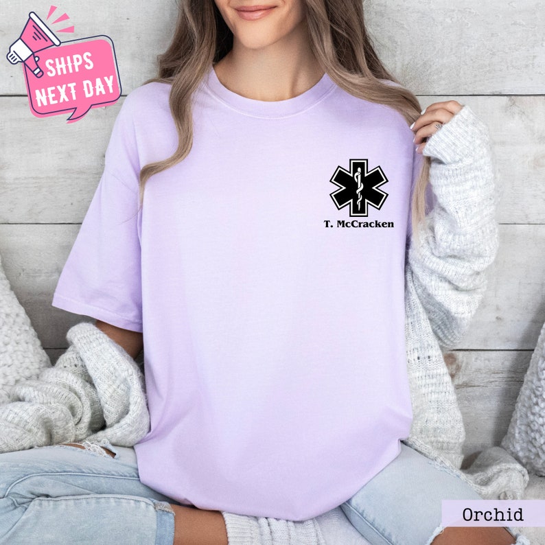 a woman wearing a purple t - shirt with a cross on it
