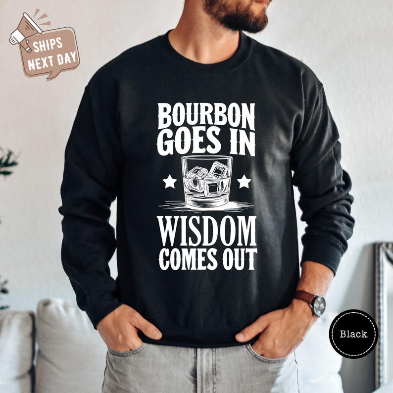 a man wearing a black sweatshirt that says bourbon goes in wisdom comes out
