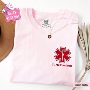 a pink t - shirt with a red cross on it