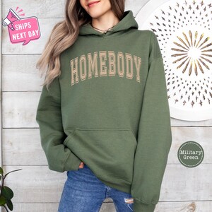 a woman wearing a green hoodie with the words homeboy on it