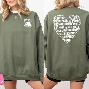 a woman wearing a green sweatshirt with white writing on it