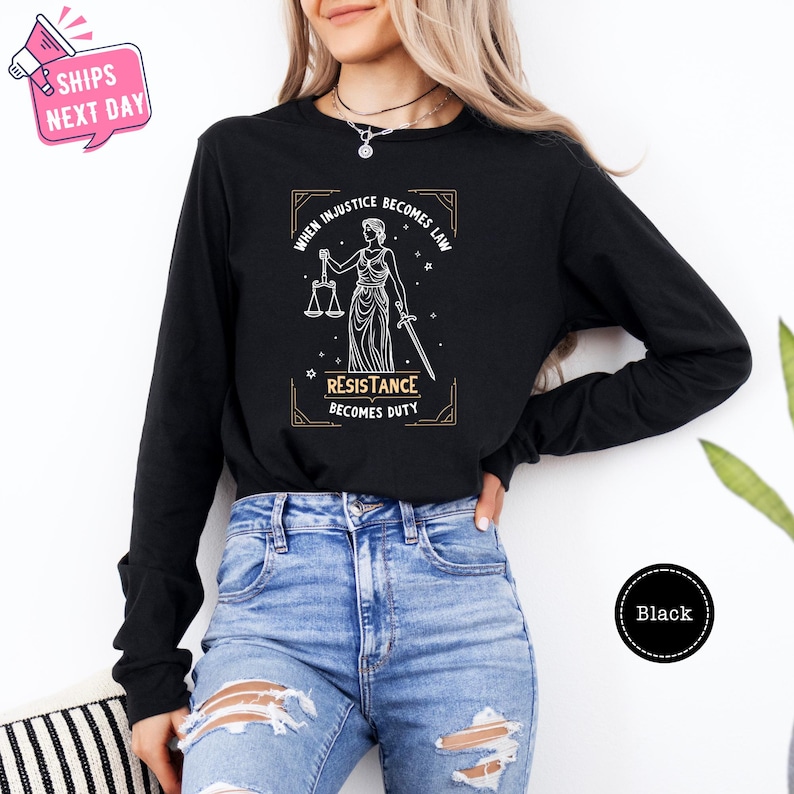 a woman wearing a black shirt with a lady holding a scale of justice on it